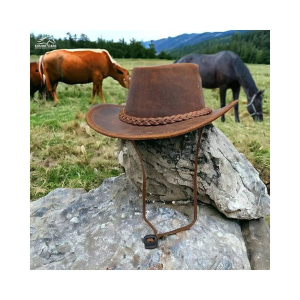 Equiencares genuine leather cowboy hat placed on rock in ranch setting with cattle in background